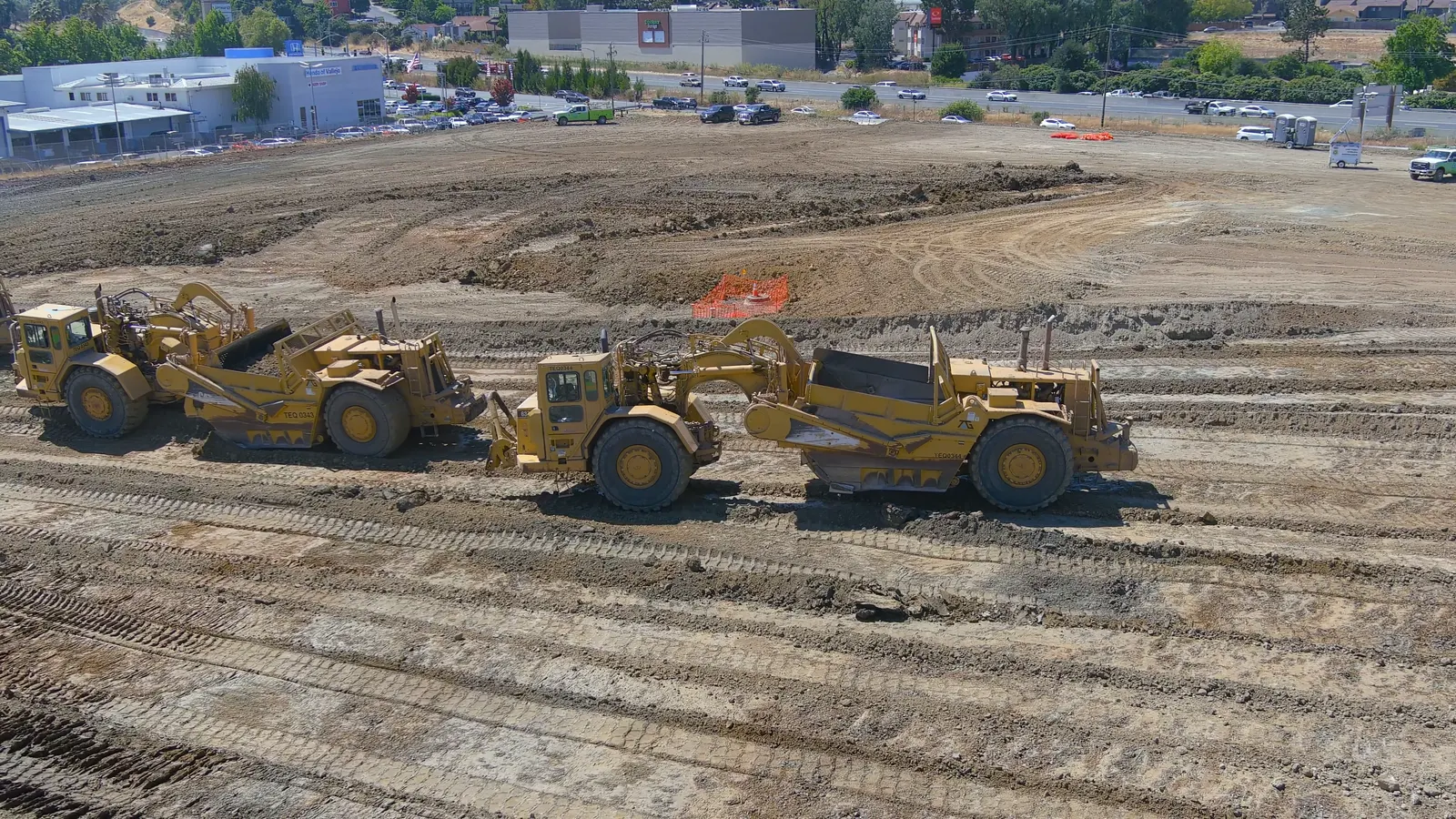 Scrapers moving earth across a graded site